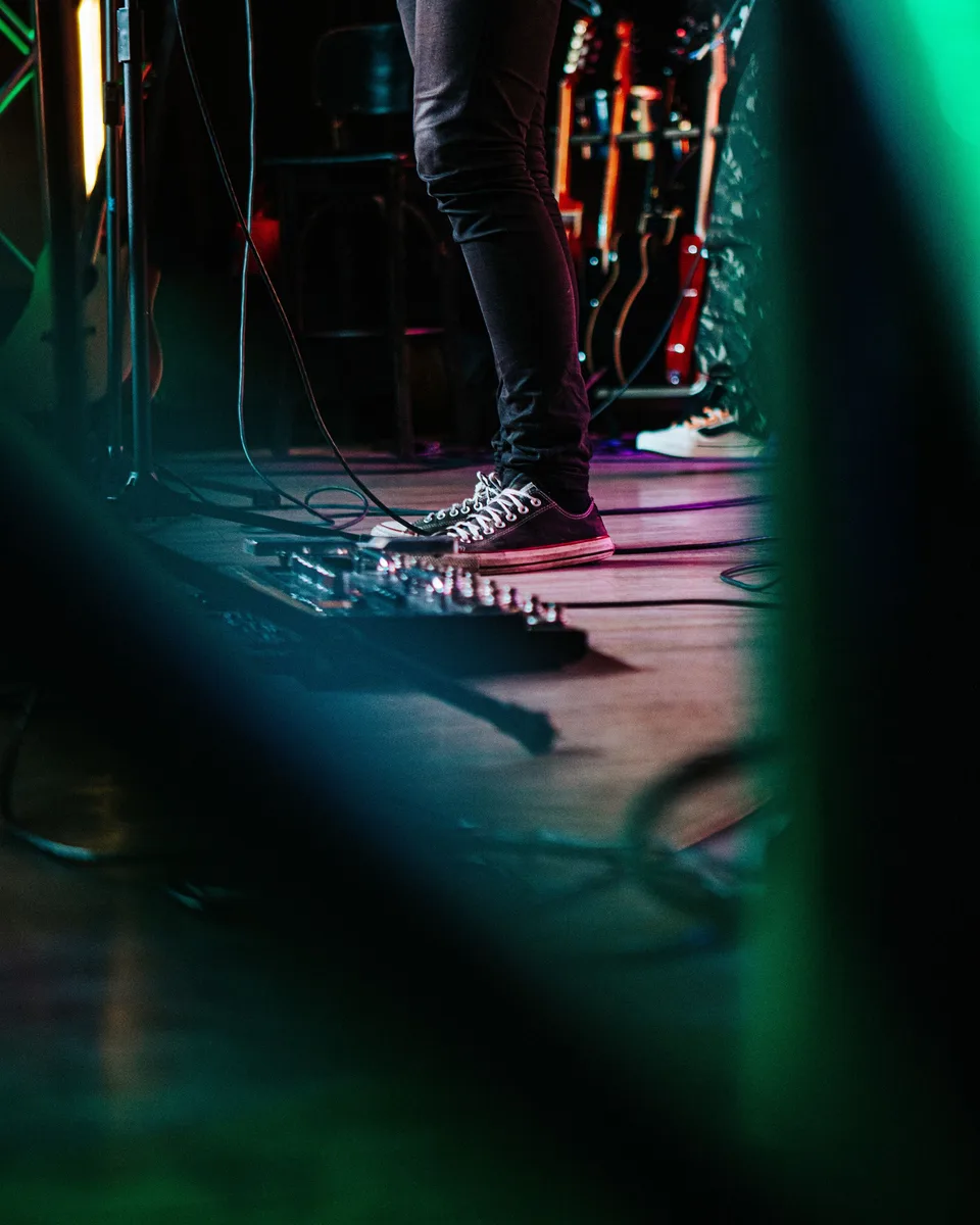 Səhnədə musiqiçi gitara pedalının yanında